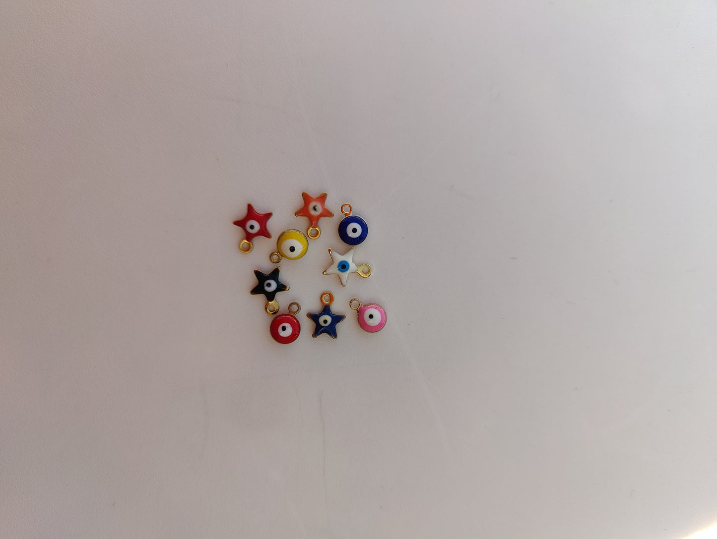 Colorful stainless steel charms for jewelry customization, featuring stars and circular designs.