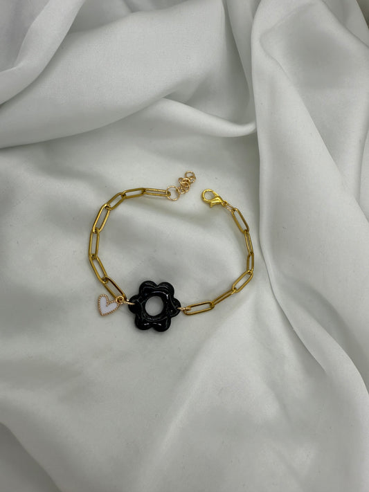 Bracelet doré, maille rectangle d'une largeur de 4 mm avec motif fleur 6 pétales de couleur noir d'environ 2,5 cm  et un charm cœur blanc entouré de doré. 